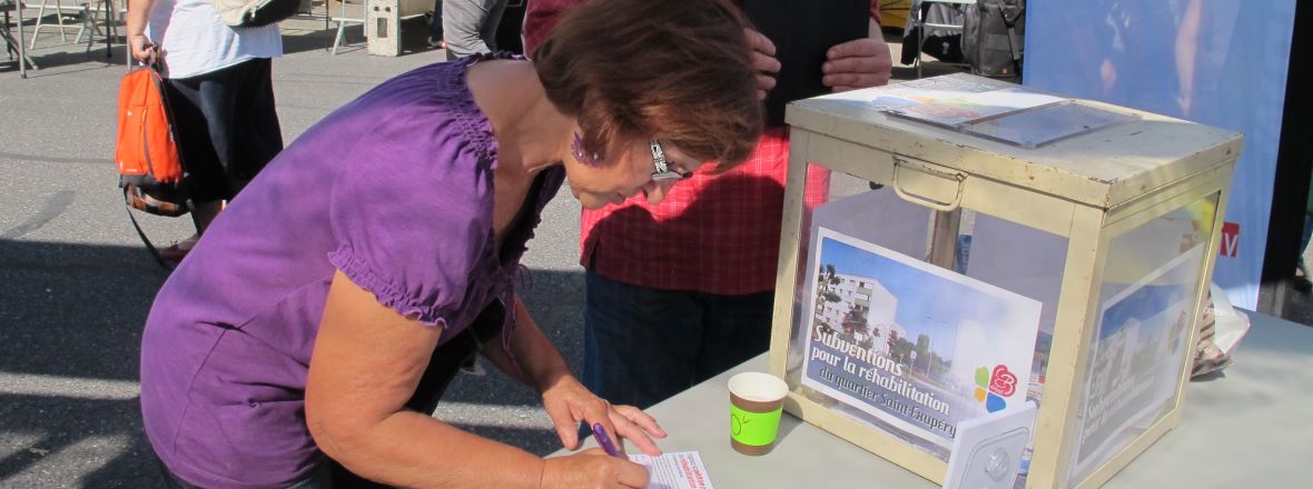 Habitante signant la pétition pour la réhabilitation de la cité Saint-Exupéry